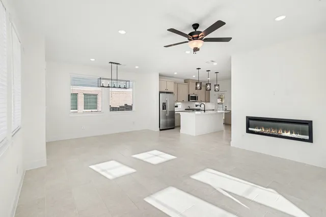 a view of an empty room with kitchen and window