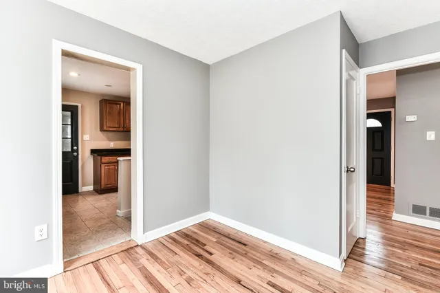a view of a hallway with wooden floor and a kitchen