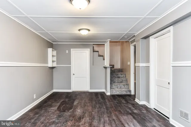 a view of an empty room with wooden floor and closet