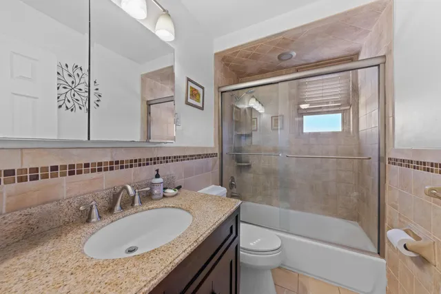 a bathroom with a granite countertop sink toilet and shower