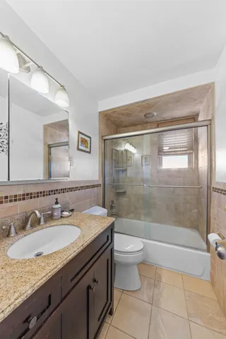 a bathroom with a granite countertop sink a toilet and shower