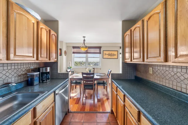 a dining room with stainless steel appliances granite countertop lots of white furniture wooden floor and a window