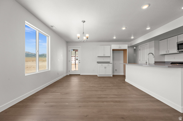 1554 Pheasant Road Eagle Mountain, UT 84005 - Photo 6 of 29 Kitchen featuring hanging lights, white cabinets, dark wood-type flooring, and stainless steel microwave