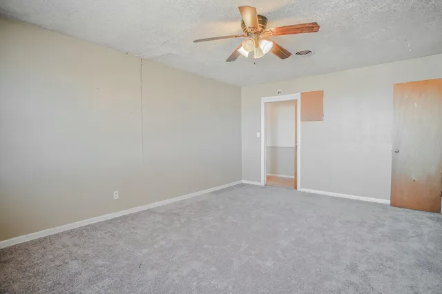 an empty room with chandelier fan and windows