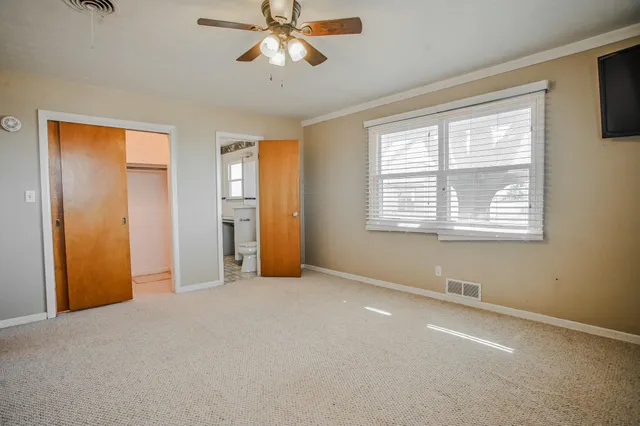 an empty room with a ceiling fan and a window