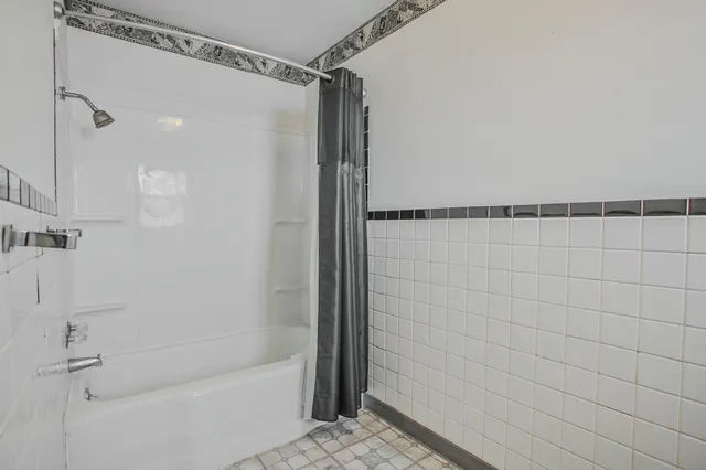 an empty room with chandelier fan and windows