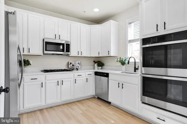 a kitchen with granite countertop white cabinets white stainless steel appliances and a sink