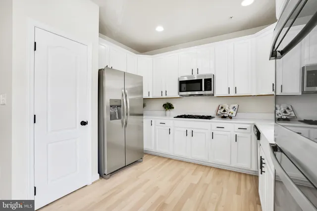 a kitchen with granite countertop white cabinets and stainless steel appliances
