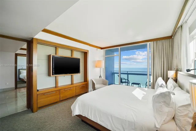 a bedroom with a bed and a flat tv screen on dresser