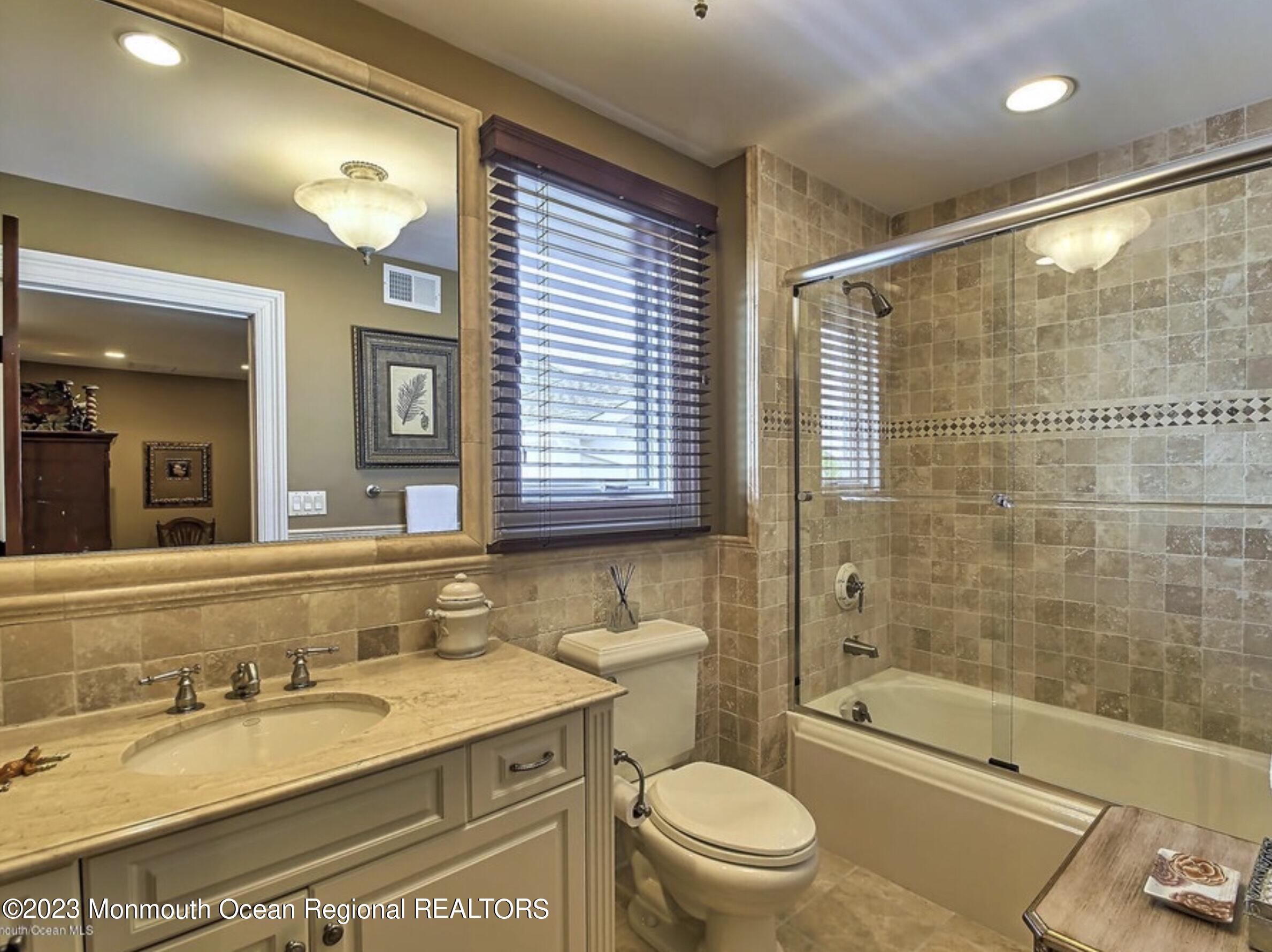 220 Pointe Drive Mantoloking, NJ 08738 - Photo 23 of 30 a bathroom with a granite countertop sink toilet mirror and bathtub