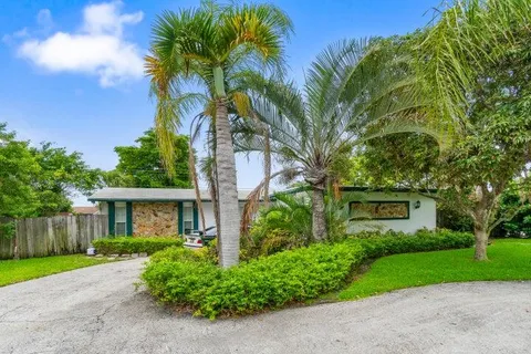 a view of a house with a yard and palm trees