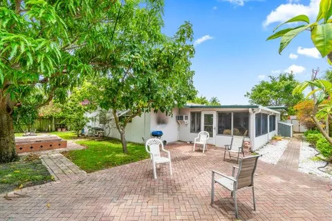 a view of a patio with table and chairs potted plants and large tree