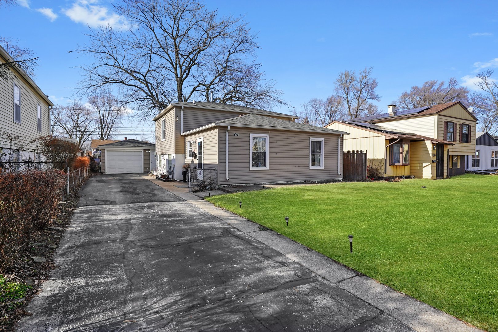 298 Merrill Avenue Calumet City, IL 60409 - Photo 2 of 13 a view of a yard in front of a brick house with a large tree