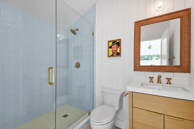 a bathroom with a shower a sink a toilet and mirror