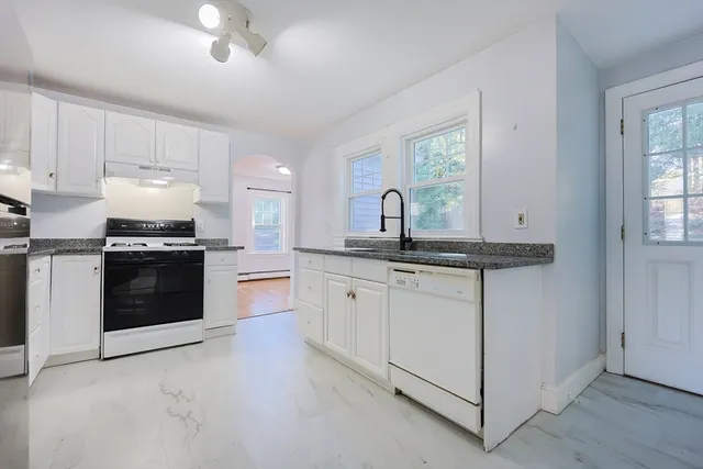 a kitchen with granite countertop white cabinets and white appliances