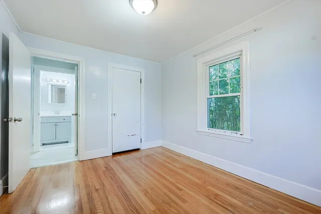 an empty room with wooden floor closet and windows