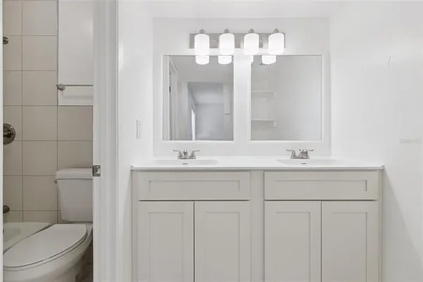 a bathroom with a double vanity sink mirror and toilet