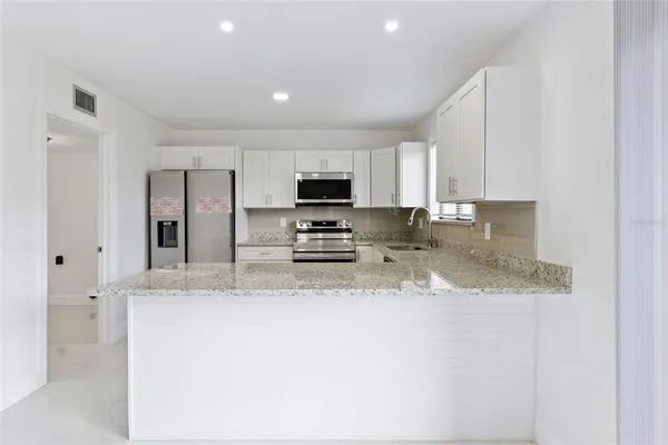 a kitchen with stainless steel appliances granite countertop a sink a stove and a refrigerator