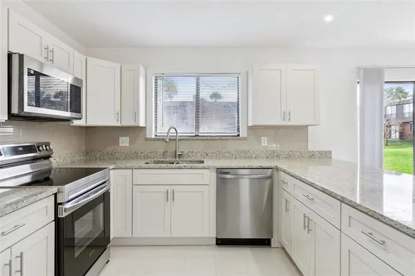 a kitchen with stainless steel appliances granite countertop a sink and dishwasher a stove top oven with white cabinets