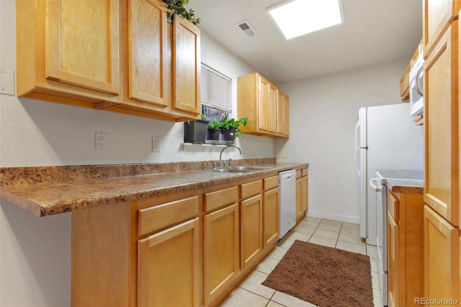 2265 South Buckley Road, Unit 102 Aurora, CO 80013 - Photo 12 of 28 a kitchen with stainless steel appliances granite countertop a refrigerator a sink dishwasher and cabinets next to a window