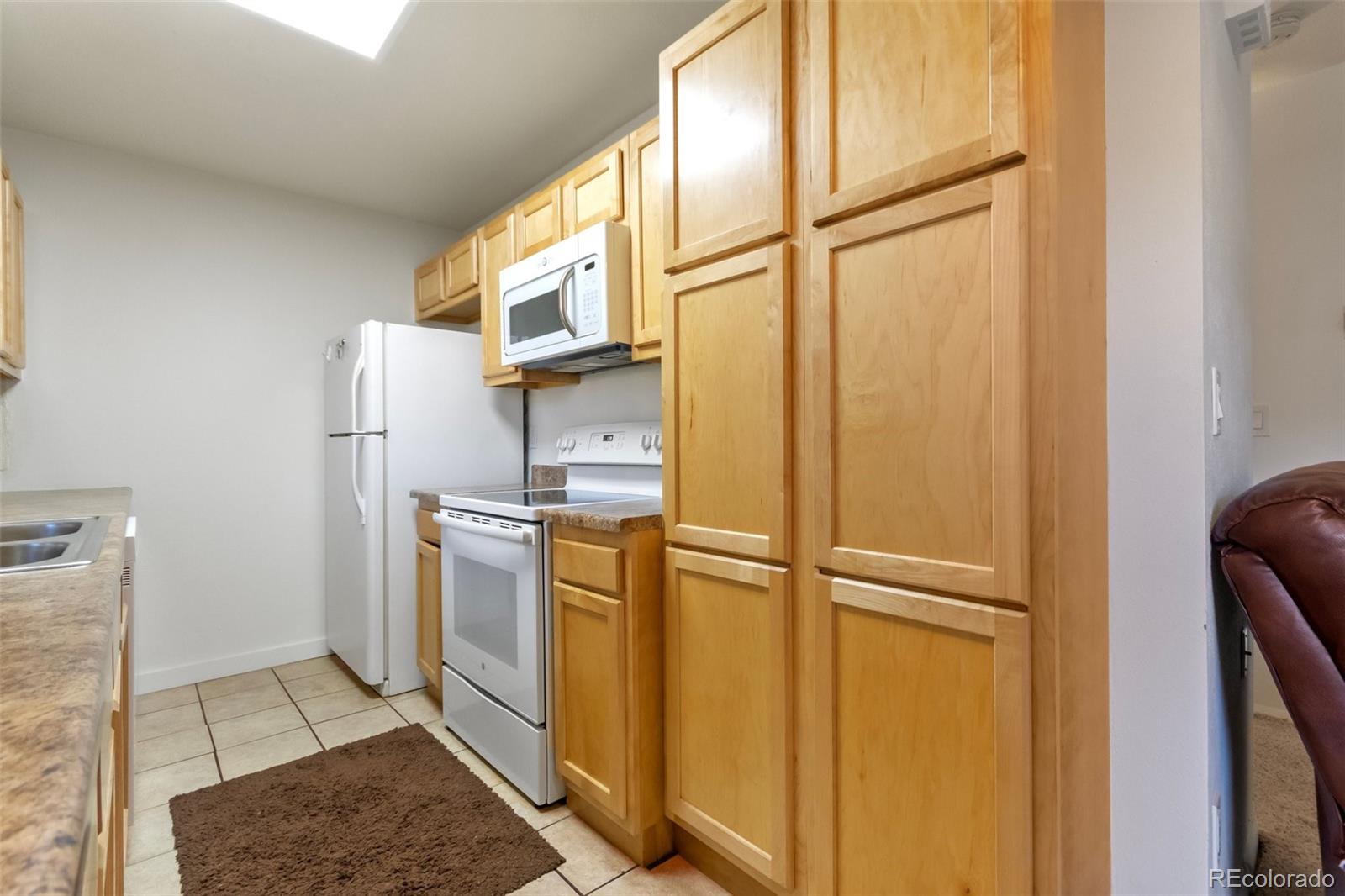 2265 South Buckley Road, Unit 102 Aurora, CO 80013 - Photo 13 of 28 a kitchen with a refrigerator and white cabinets