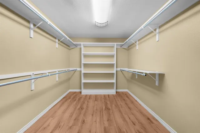 an empty room with wooden floor fireplace and windows