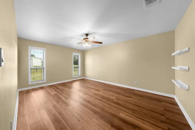 a view of a room with wooden floor and a ceiling fan