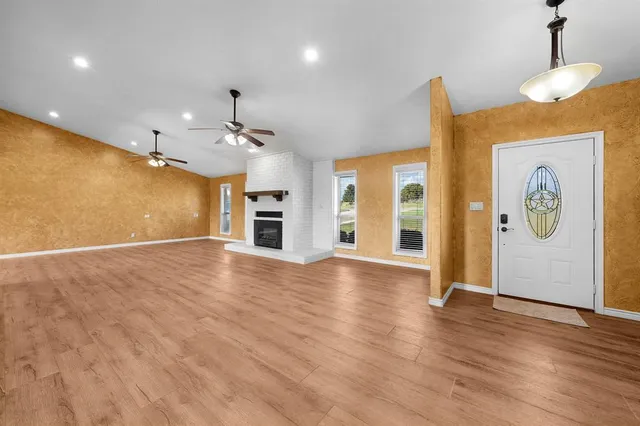a view of an empty room with window and wooden floor