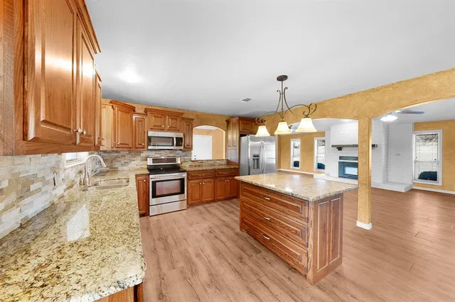 a kitchen with stainless steel appliances granite countertop a stove a sink dishwasher and a refrigerator with wooden floor