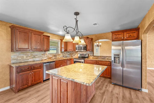 a kitchen with stainless steel appliances granite countertop a sink a stove and refrigerator