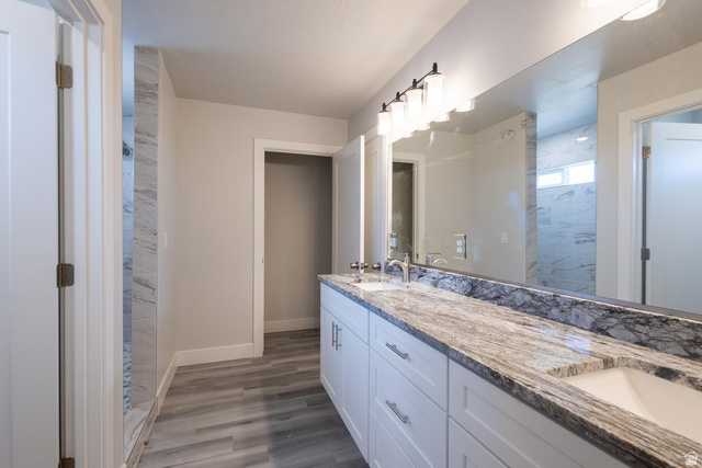 910 East Remington Road Cedar City, UT 84721 - Photo 27 of 29 Dual vanity featuring white shaker cabinetry, polished chrome hardware, and a stone countertop with integrated sinks
