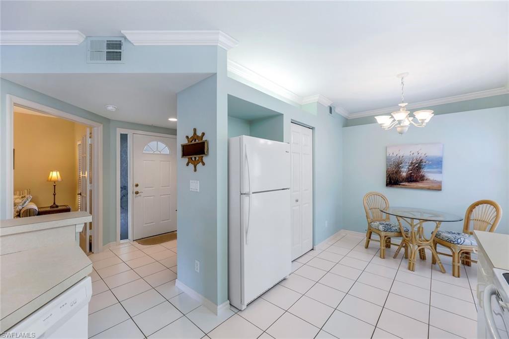 23711 Old Port Road, Unit 101 Estero, FL 34135 - Photo 11 of 30 Kitchen with ornamental molding, a chandelier, light tile patterned floors, and white appliances