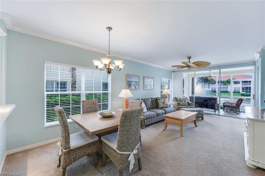 23711 Old Port Road, Unit 101 Estero, FL 34135 - Photo 13 of 30 Dining area featuring ornamental molding, ceiling fan with notable chandelier, and light carpet
