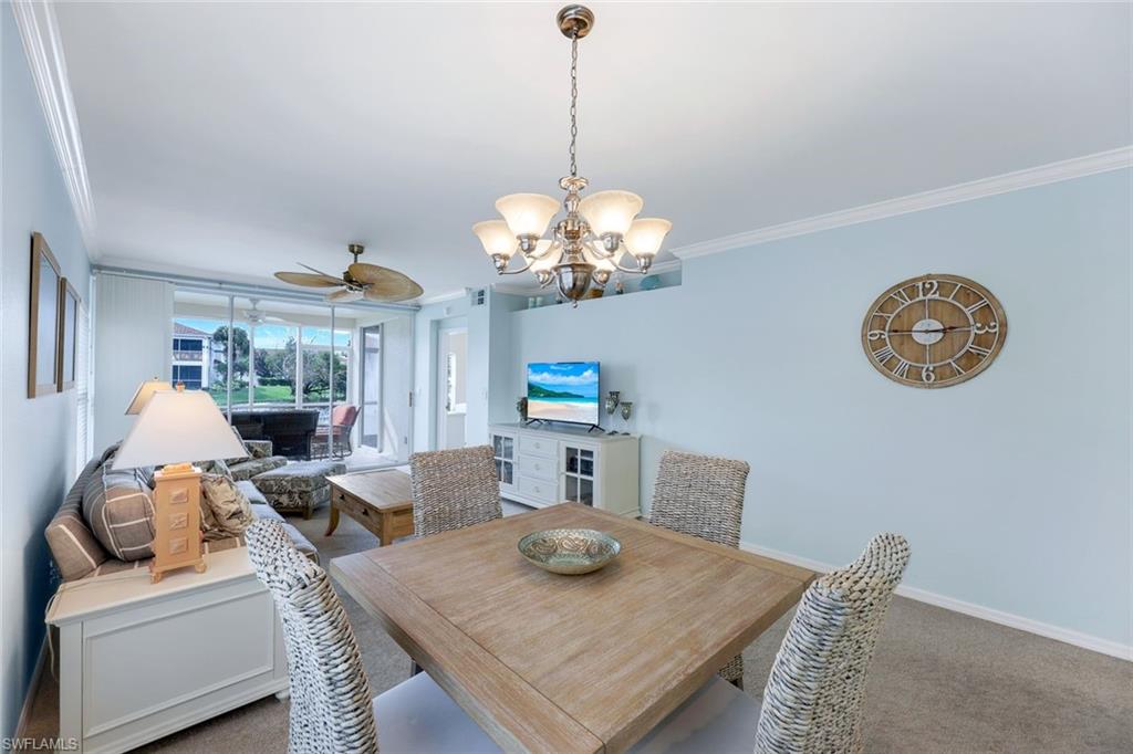 23711 Old Port Road, Unit 101 Estero, FL 34135 - Photo 14 of 30 Carpeted dining room with ceiling fan with notable chandelier and crown molding