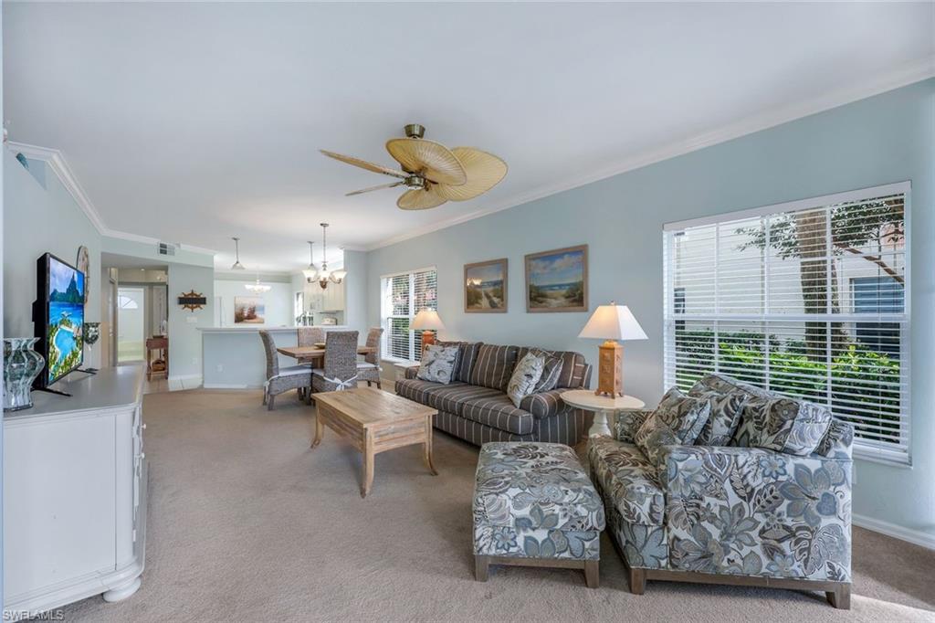 23711 Old Port Road, Unit 101 Estero, FL 34135 - Photo 5 of 30 Carpeted living room featuring ornamental molding and ceiling fan with notable chandelier