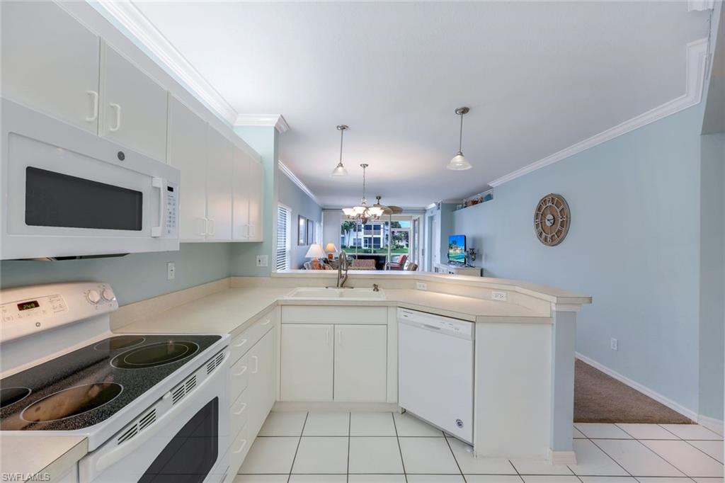 23711 Old Port Road, Unit 101 Estero, FL 34135 - Photo 9 of 30 Kitchen featuring white appliances, hanging light fixtures, sink, white cabinets, and kitchen peninsula