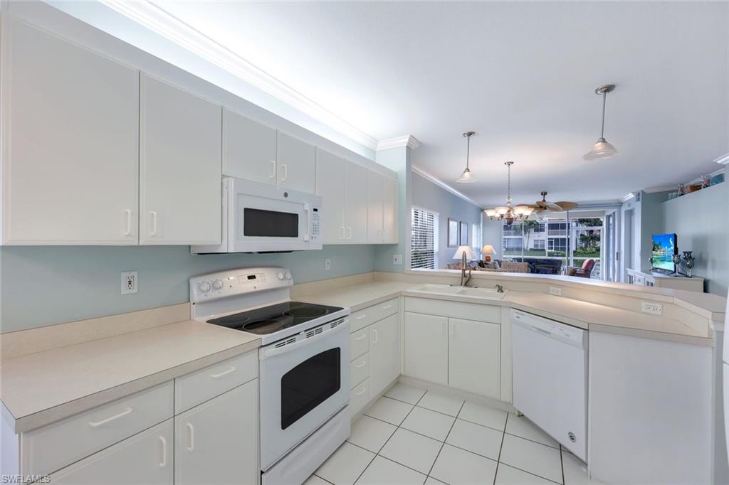 23711 Old Port Road, Unit 101 Estero, FL 34135 - Photo 10 of 30 Kitchen with white cabinets, kitchen peninsula, crown molding, white appliances, and decorative light fixtures