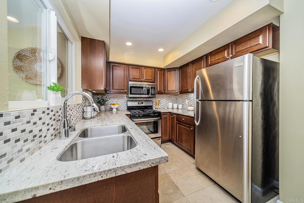 a kitchen with kitchen island granite countertop a sink refrigerator and microwave