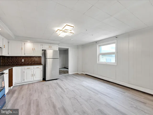 a view of a kitchen with a refrigerator a stove top oven and cabinets