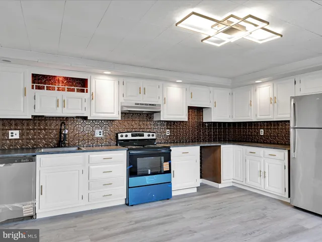 a kitchen with stainless steel appliances white cabinets a sink and wooden floor