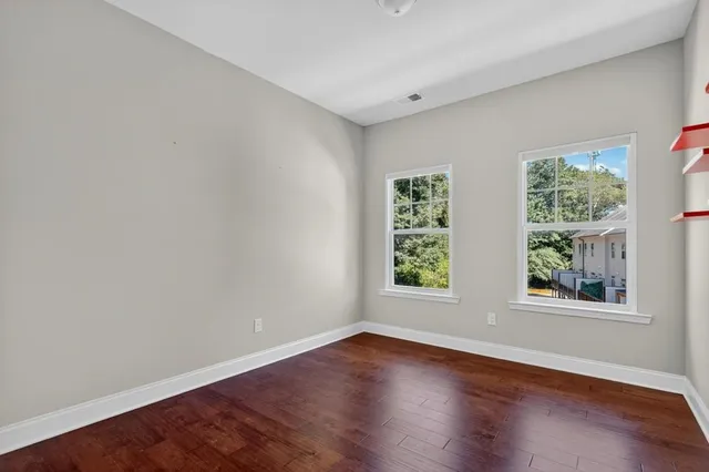 an empty room with wooden floor and windows