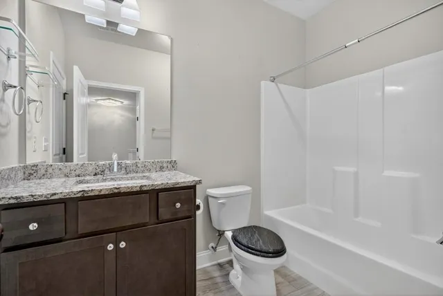a bathroom with a granite countertop sink toilet and a mirror