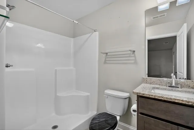 a bathroom with a granite countertop sink toilet and shower