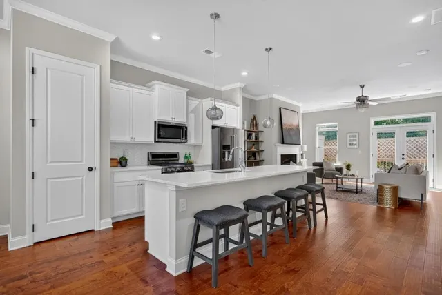a large white kitchen with lots of counter space dining table and stainless steel appliances