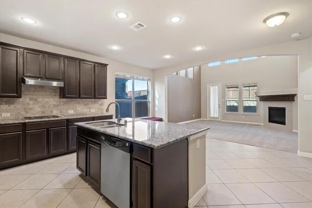 a kitchen with granite countertop stainless steel appliances a sink stove top oven and cabinets