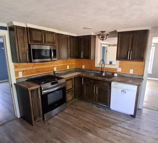 a kitchen with stainless steel appliances granite countertop a stove a sink and a microwave