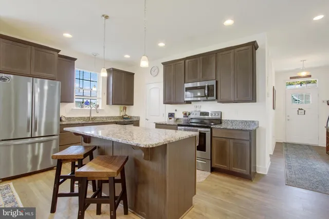 a kitchen with stainless steel appliances granite countertop a sink a stove a refrigerator and a refrigerator