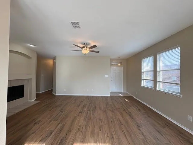 a view of an empty room with window and wooden floor