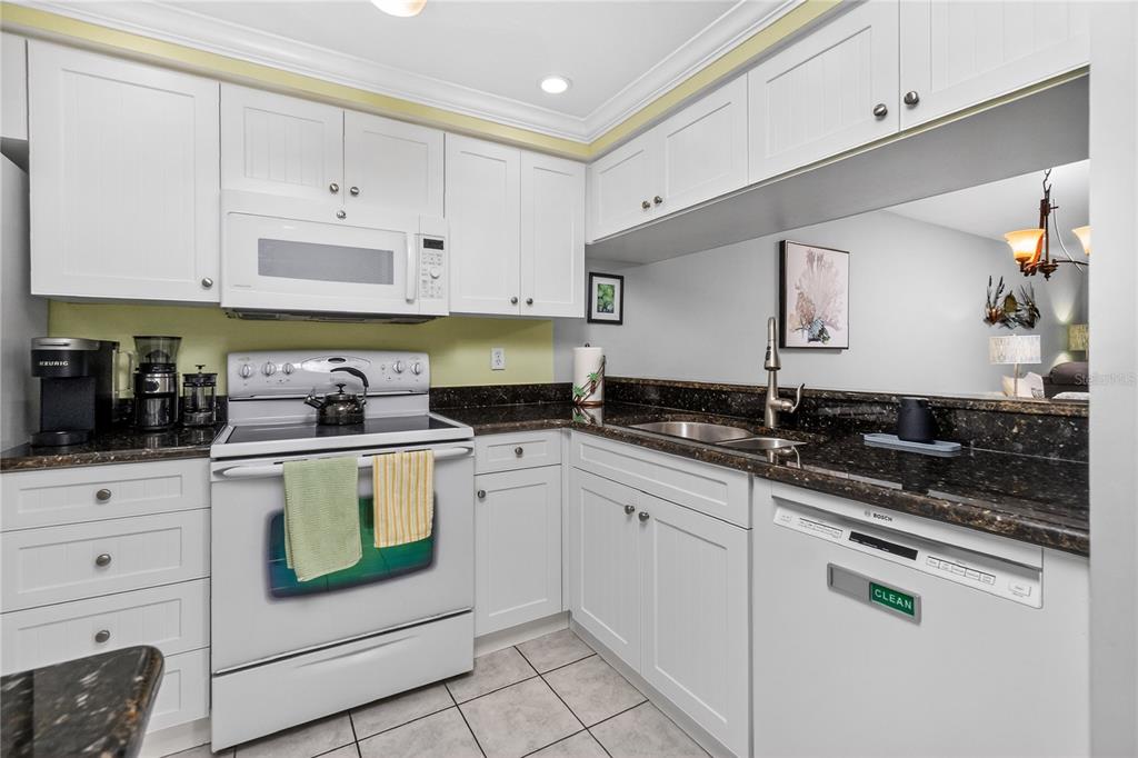 1501 Beach Road, Unit 210 Englewood, FL 34223 - Photo 9 of 62 a kitchen with granite countertop white cabinets and white appliances