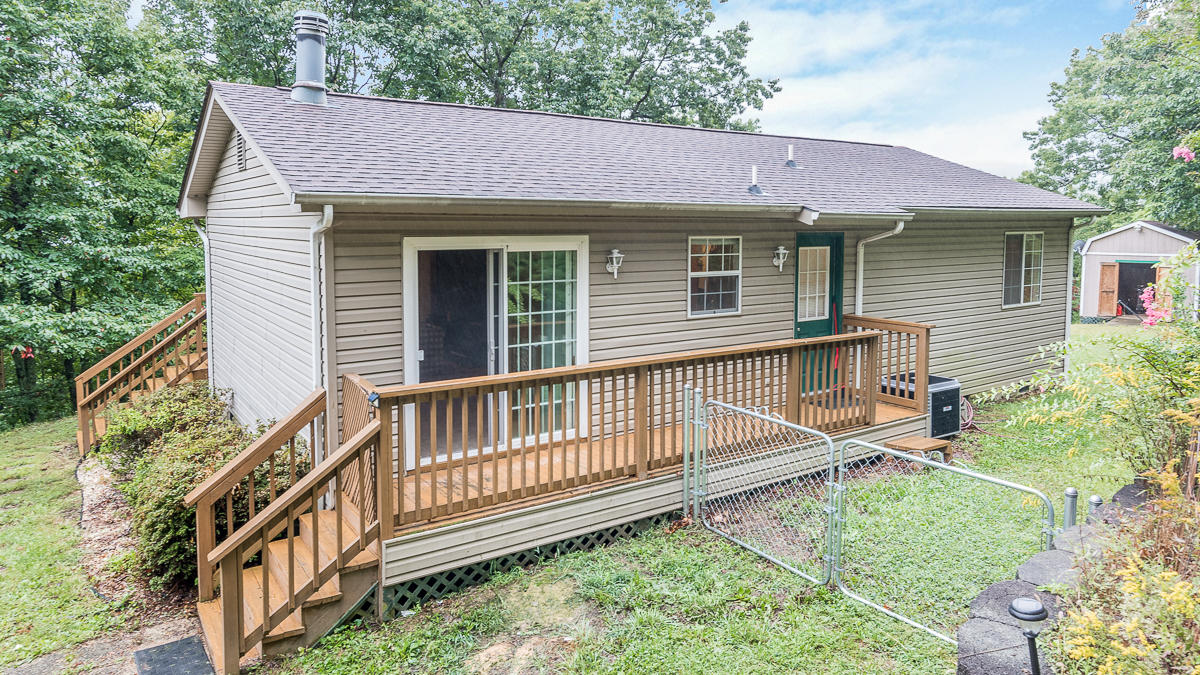 a view of a house with a small yard and wooden deck